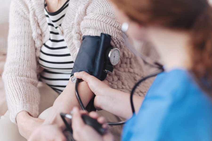 A clinician takes the blood pressure of a patient
